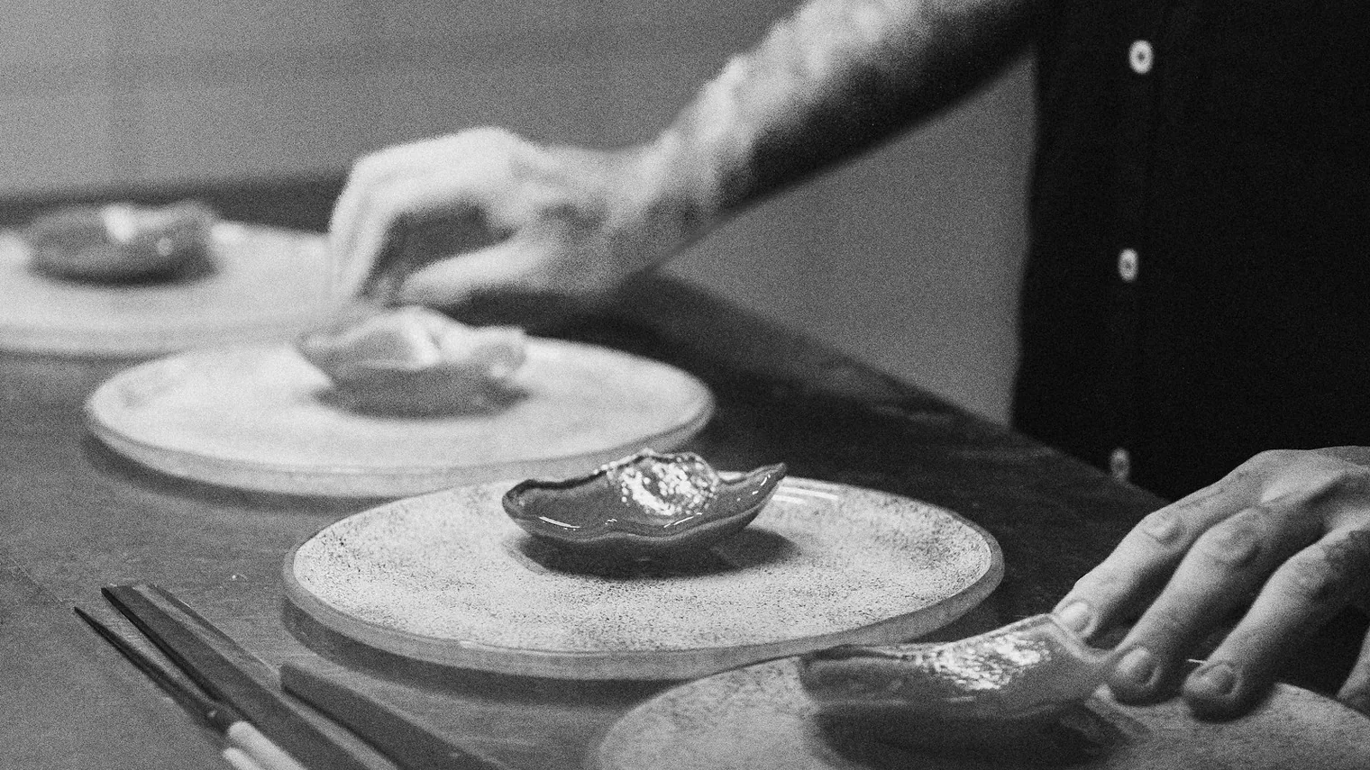 Mãos de chef preparando ostras sobre uma tábua
